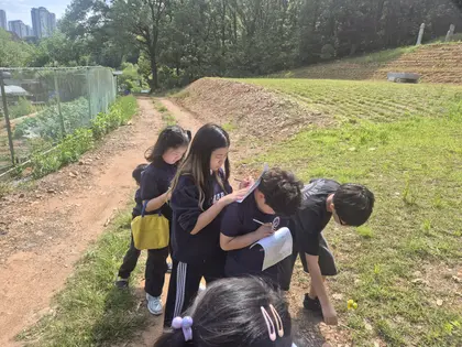 숲길에서 무언가를 관찰하는 학생들