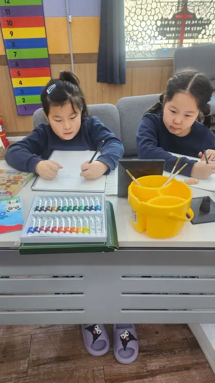 책상에 앉아 그림을 그리는 어린 학생
